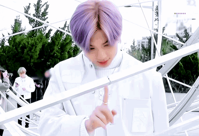 a man with purple hair and a white jacket is pointing
