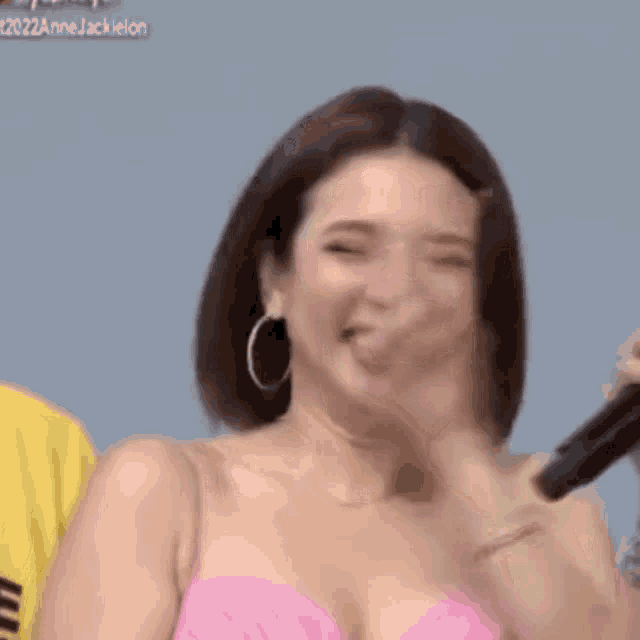 a woman in a pink dress is giving a peace sign .