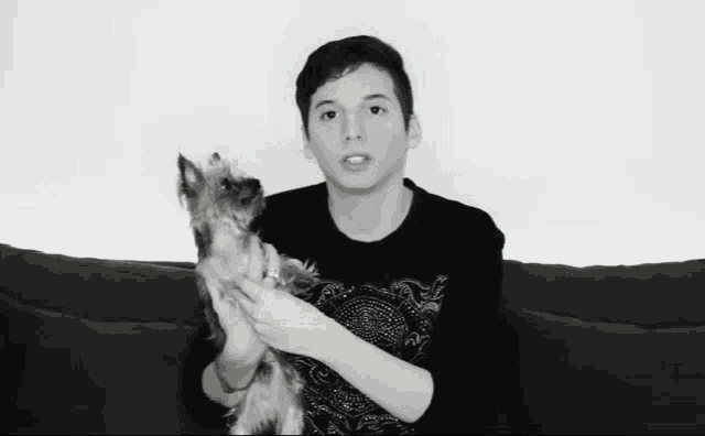 a young man is holding a small dog in his hands