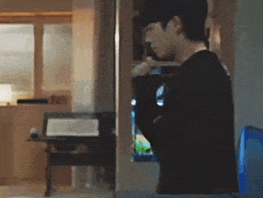 a man in a black shirt is standing in front of a refrigerator in a kitchen .