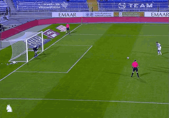a soccer game is being played on a field with emaar advertisements on the sidelines