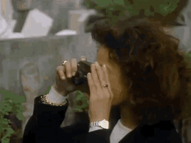 a woman is taking a picture with a camera while wearing a watch .