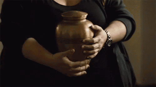 a woman is holding a brass urn in her hands .