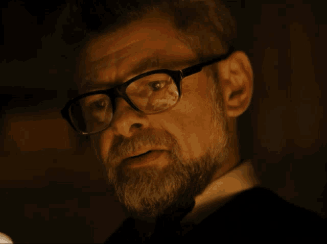 a man with glasses and a beard is looking at the camera
