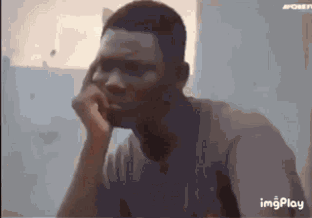 a man is sitting at a table with his hand on his chin and looking at the camera .