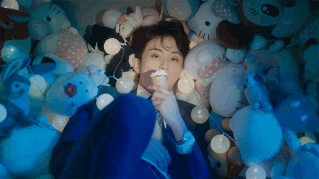 a man in a blue suit is surrounded by stuffed animals and lights