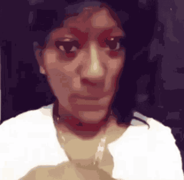 a woman is making a funny face while wearing a white shirt .