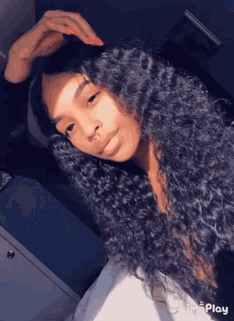 a woman with curly hair and a nose ring looks at the camera with imgplay at the bottom of the screen