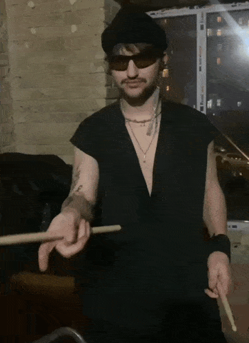 a man wearing sunglasses holds a drum stick