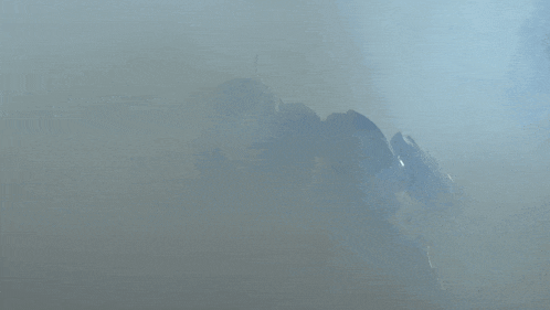 a robot with a sword and shield is surrounded by a cloud of smoke
