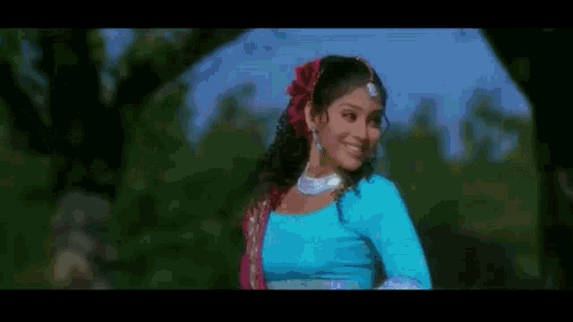 a woman in a blue dress is smiling in front of a tree .