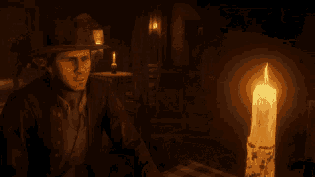 a man in a cowboy hat sits at a table with a lit candle