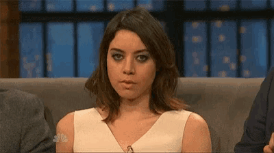 a woman is sitting on a couch making a funny face .