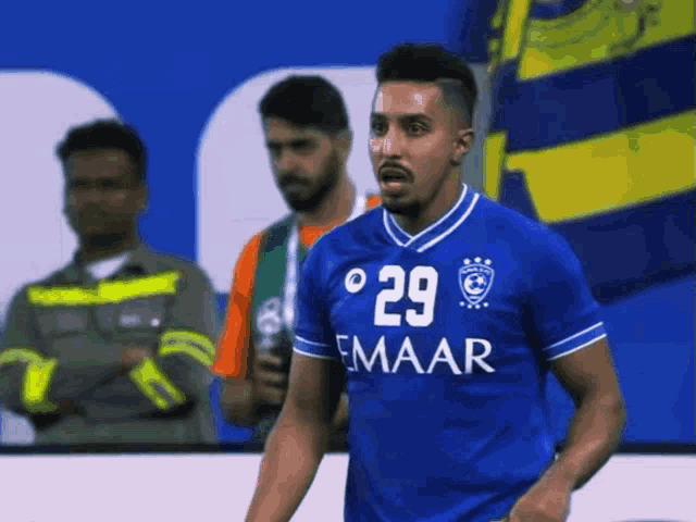 a soccer player wearing a blue jersey that says 29 emaar