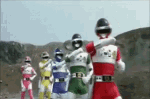 a group of power rangers are standing next to each other in a field .