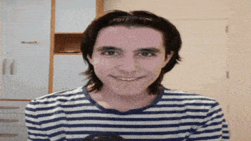 a man wearing a blue and white striped shirt smiles