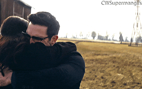 a man and woman hugging in a field with the words cwsupermangifs on the bottom right