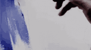 a person is painting a picture on a white wall with a blue and white brush .