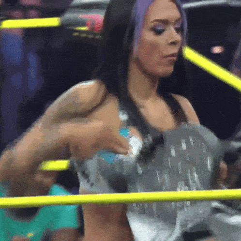 a woman with purple hair is standing in a boxing ring