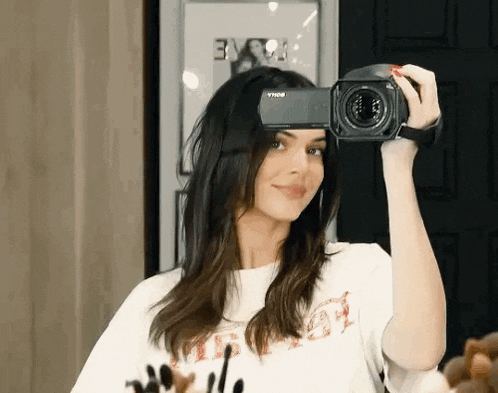a woman is taking a picture of herself in a mirror with a video camera .