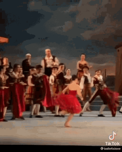 a woman in a red dress is dancing on a stage with other people