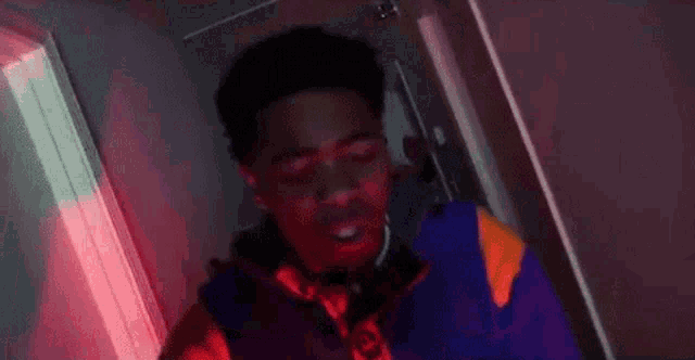 a young man in a purple jacket and tie is standing in a hallway .