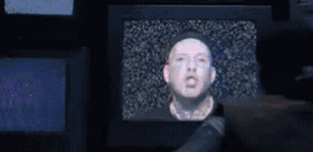 a man with a television instead of a head is surrounded by colorful circles