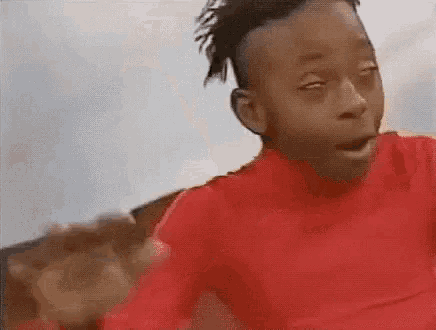 a young boy in a red shirt is making a funny face with his eyes closed .