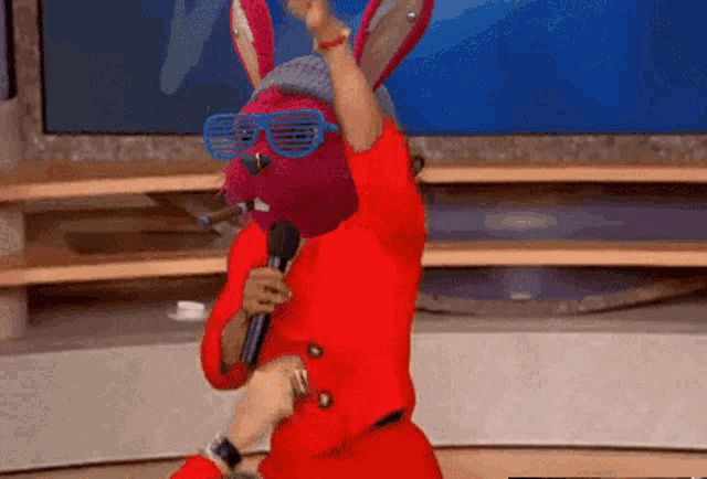 a person wearing a bunny mask and sunglasses is singing into a microphone
