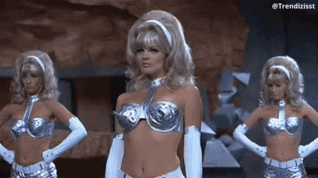 three women are standing next to each other in silver costumes .
