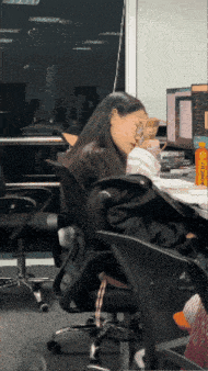 a woman sits at a desk in front of a computer with a bottle that says ' l' oreal '
