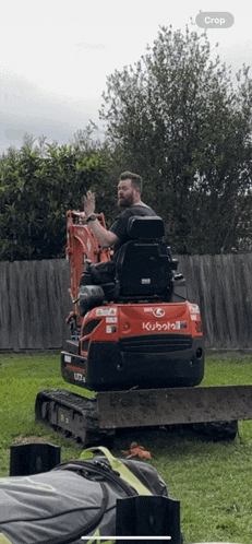 a man is sitting on a kubota bulldozer in a yard