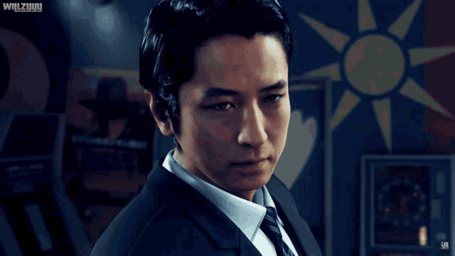 a man in a suit and tie stands in front of a sign that says wilzyuyy