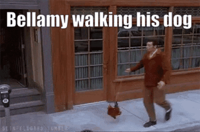 a man is walking his dog on a sidewalk in front of a building