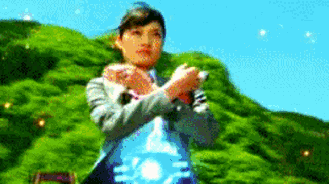a woman in a suit is standing in front of a green hill holding a blue object .
