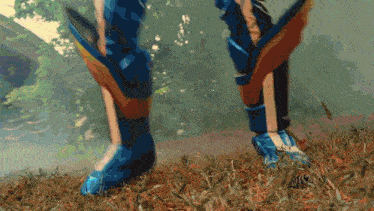 a person wearing a pair of blue and orange high heels standing in the grass