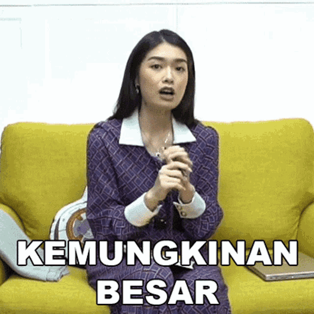 a woman is sitting on a yellow couch with the words " kemungkinan besar " written on it