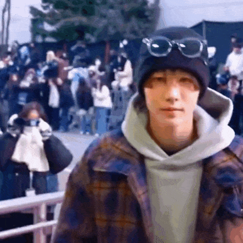 a man wearing a beanie and goggles is standing in front of a crowd of people .