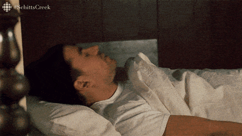 a man is sleeping in a bed with the word schitts creek on the bottom