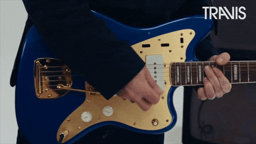 a man in a suit is playing a blue guitar with the word travis in the corner