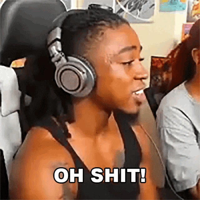 a man wearing headphones is sitting in a chair and says oh shit .