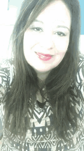 a woman with long dark hair is smiling and wearing a black and white shirt