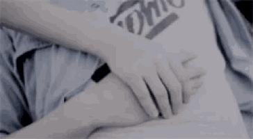 a person with a tattoo on their arm is laying down with their hands on their stomach .