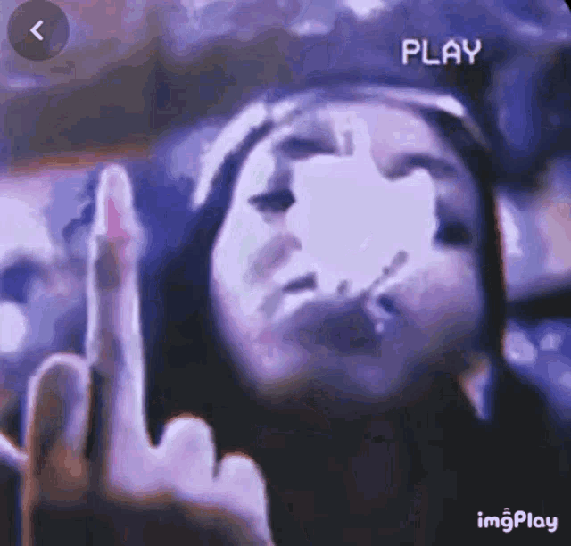 a woman is smoking a cigarette and making a middle finger gesture .
