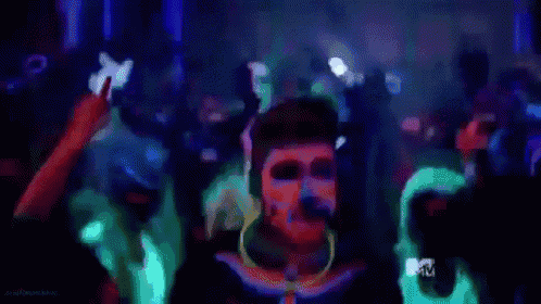 a woman with glow in the dark paint on her face is dancing in a crowd at a party