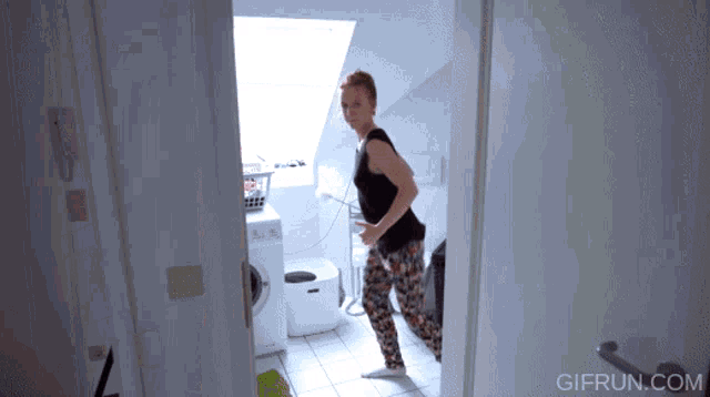 a woman dancing in a bathroom with gifrun.com written on the bottom right