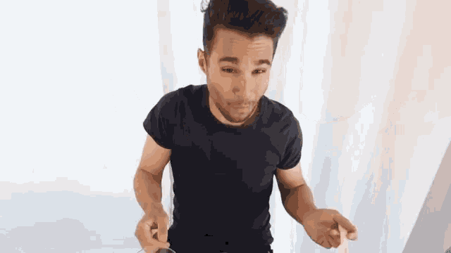 a man in a black t-shirt is holding something in his hands