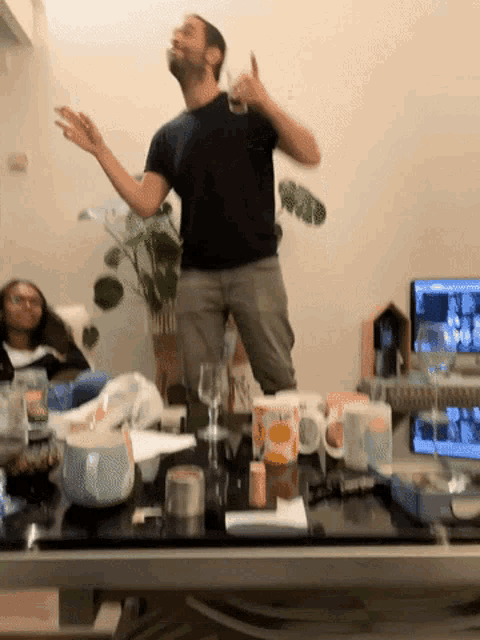 a man in a black shirt is standing in front of a table with cups and glasses on it