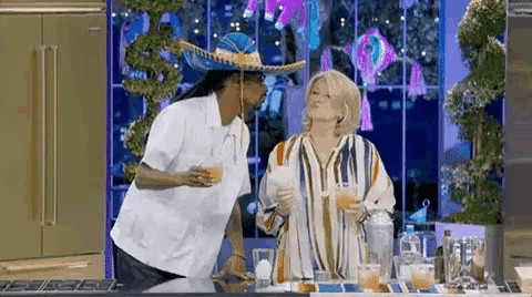 a man in a sombrero is standing next to a woman holding a drink .