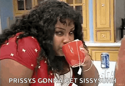 a woman is drinking from a red cup while sitting at a table in a kitchen .